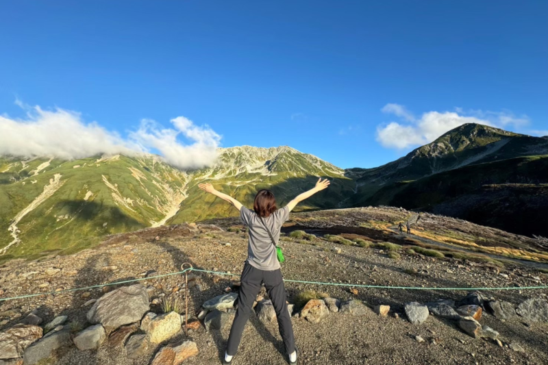 山小屋の外でサコッシュを身につけて山の景色を楽しむ様子